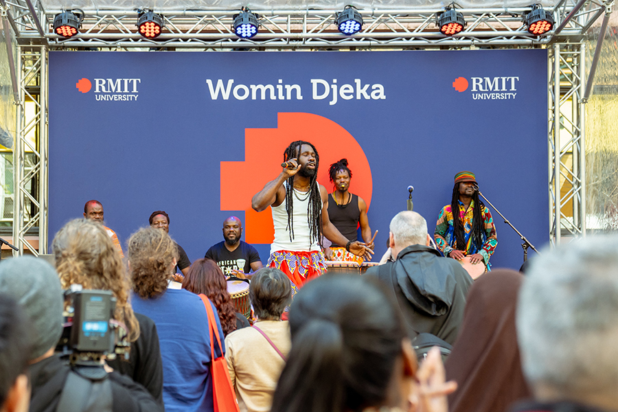 A band performs on a stage for a crowd at RMIT Open Day.